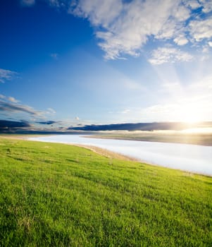 sunset over river and green grass