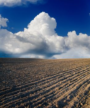 black ploughed field under cloudy sky