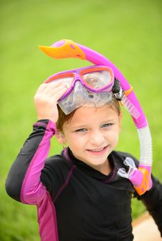 smiling young girl with swimming goggles and snorkel after getting out of the pool