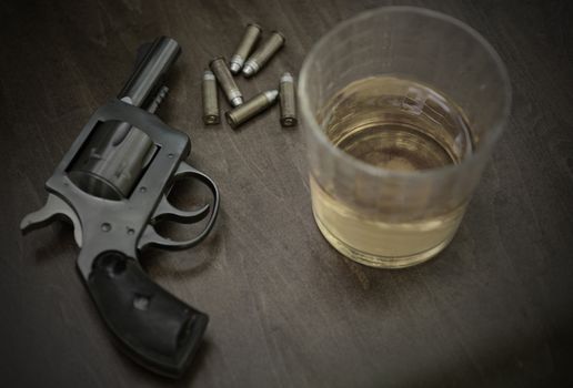 a pistol on a grunge wood background with bullets, guns and whisky