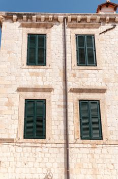 Framed ancient windows with green shutters in a rows.