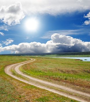 sun and clouds over dirty road