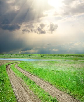 rural road in green grass under dramatic sky