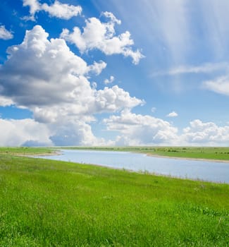 green grass and cloudy sky with river