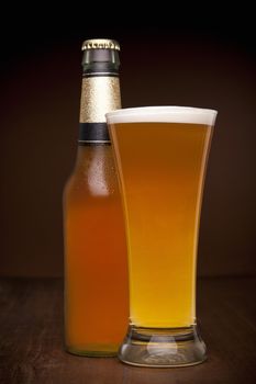 A glass and a bottle of beer on a wooden table.