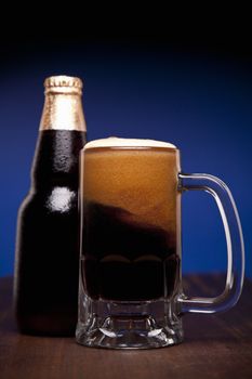 A glass and a bottle of beer on a wooden table.