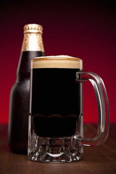 A glass and a bottle of beer on a wooden table.