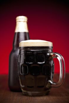 A glass and a bottle of beer on a wooden table.