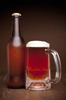 A glass and a bottle of beer on a wooden table.