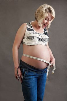 beautiful smiling pregnant woman tenderly measuring her tummy