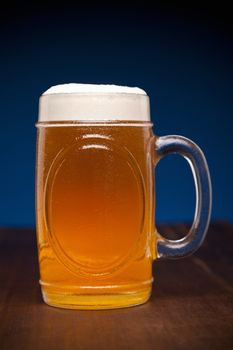 A glass of beer on a wooden table.