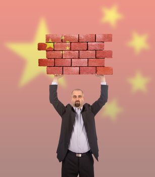 Businessman holding a large piece of a brick wall, flag of China, isolated on national flag
