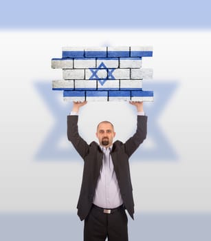 Businessman holding a large piece of a brick wall, flag of Israel, isolated on national flag