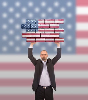 Businessman holding a large piece of a brick wall, flag of United States, isolated on national flag