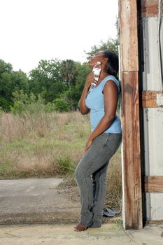 A lovely young black woman in casual wear cools off with a bottle of water.