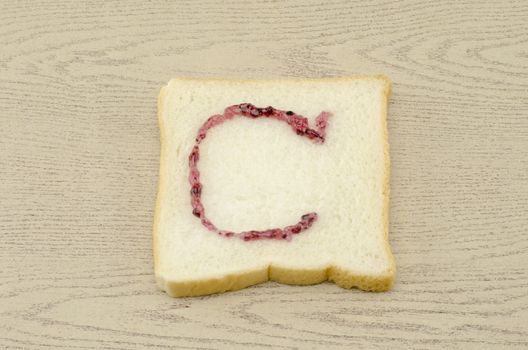 jam alphabet on sliced bread on wood background