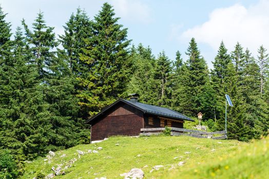 Wooden mountain refuge with solar panels and display of a holy figure in the Bavarian Alps