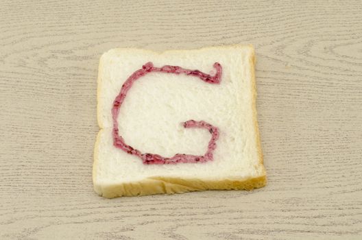 jam alphabet on sliced bread on wood background