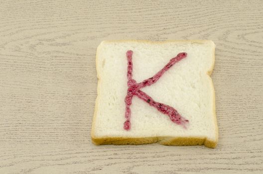 jam alphabet on sliced bread on wood background