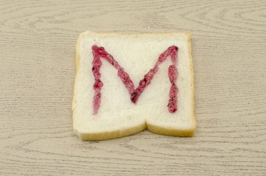 jam alphabet on sliced bread on wood background