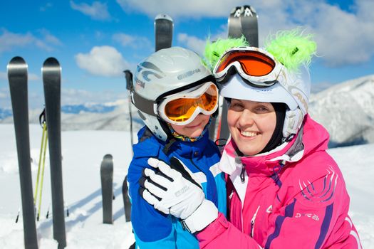 Portrait closeup of happy smiling boy in ski goggles and a helmet with his mother