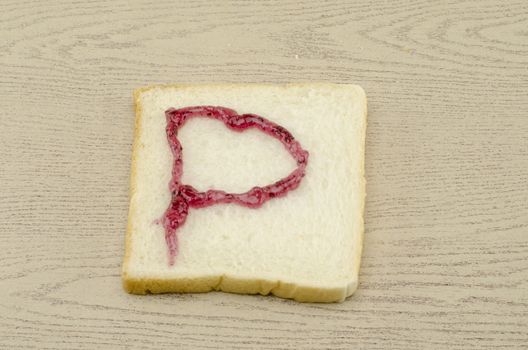 jam alphabet on sliced bread on wood background