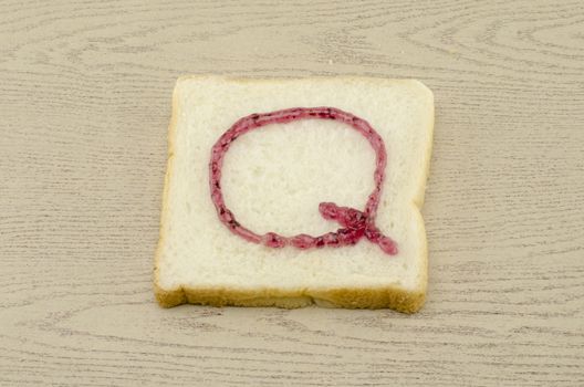 jam alphabet on sliced bread on wood background