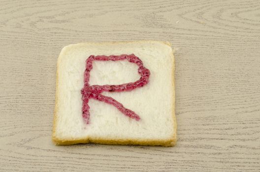 jam alphabet on sliced bread on wood background