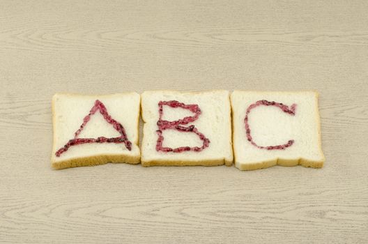 jam alphabet on sliced bread on wood background