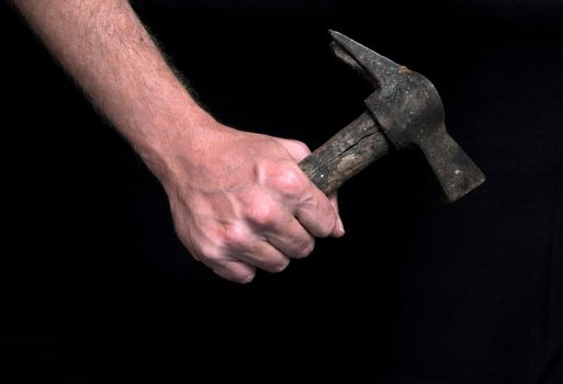 An Hand Holding an Old Hammer over a Black Background