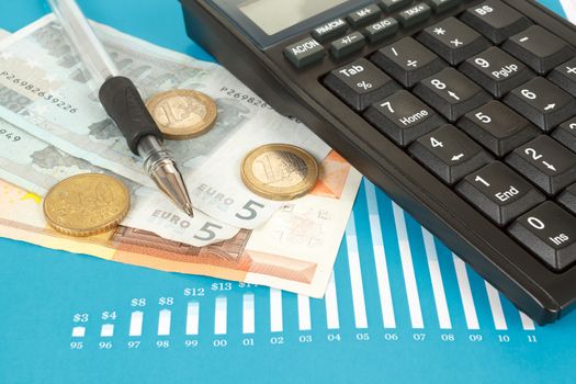 Blue stock market graphs with pen and euro coins