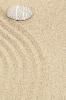 zen stone in soft sand with lines