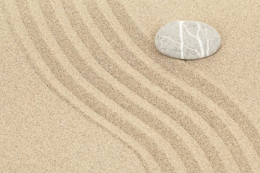 zen stone in soft sand with lines