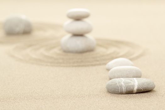 Balance of three zen stones in sand with shallow focus