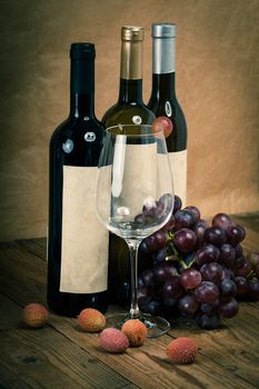 bottle of vine with wine glass and grapes, on wooden background