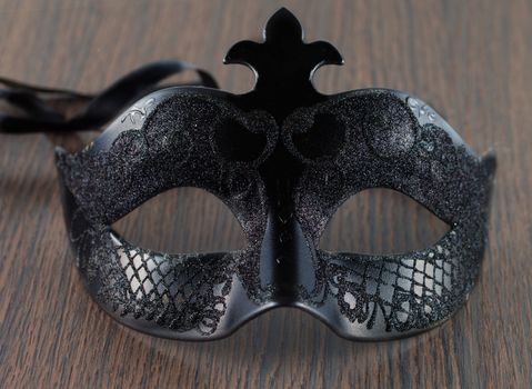 A black mask for venetian carnival over a wooden table