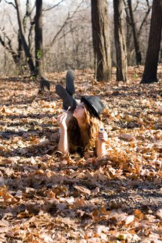 The girl in the autumn forest lying on yellow leaves inflates balloons