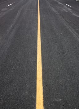 Black asphalt road, yellow lines separate lanes.