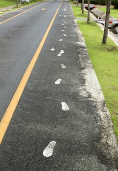 Black asphalt road, yellow lines separate lanes.