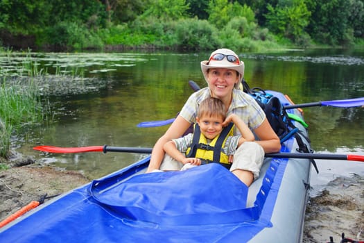 Happy young boy with mother paddling a kayak on the river, enjoying a lovely summer day