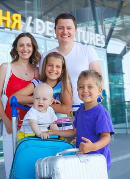 Portrait of traveling family of five with suitcases in airport