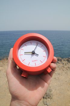 One Red Clock on the Rocks Near the Ocean 