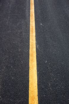 Black asphalt road, yellow lines separate lanes.