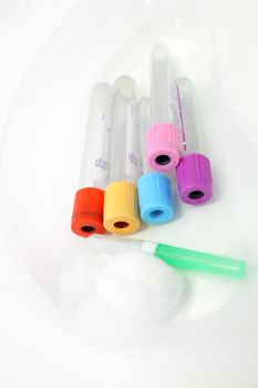 Unlabelled pathology phlebotomy, blood collecting vacutainer tubes a 21 gauge needle and cotton wool lying in a kidney dish for a blood collection procedure