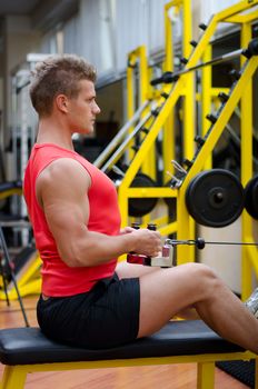 Handsome young man working out, exercising back on gym equipment