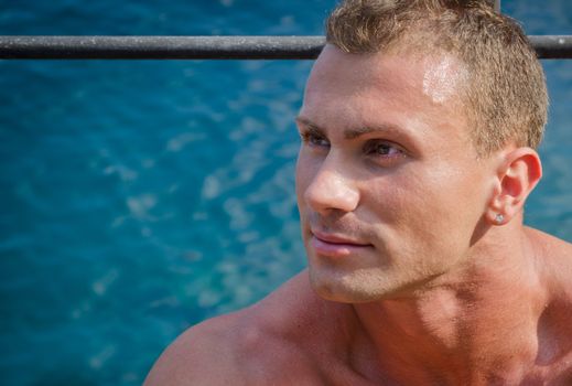 Handsome young man  looking to a side, sea behind him, large copy-space