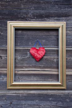 golden picture frame on old wooden wall and red heart symbol
