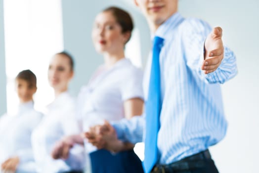 invitation to the team, the business man stretches out his hand, behind him a number of young businessmen