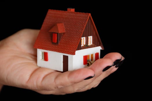 Image of dollhouse in human hand on black background
