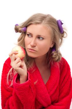 Thoughtful girl in a red bathrobe with an apple in his hand